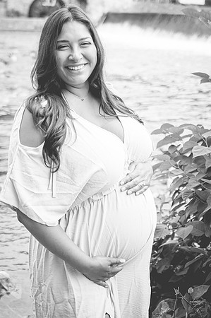 Maternity portrait featuring a smiling female with a male at a waterfall.