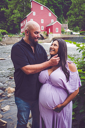 Maternity session at a waterfall with complementary colors, featuring a smiling male and female.