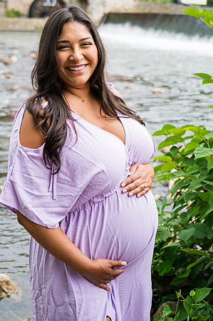 Maternity portrait of a smiling male at a waterfall.