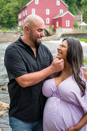 Maternity portrait by the river featuring a smiling female in profile view.
