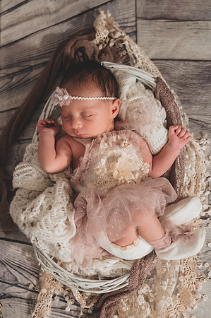 Colorful newborn session in a basket at Clinton studio with a smiling male child.
