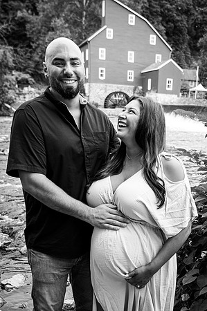 Maternity session at a waterfall with complementary colors, featuring a smiling couple.