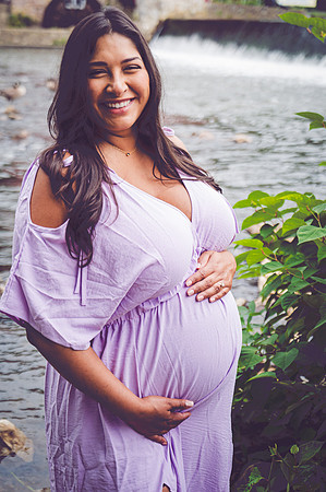 Maternity portrait of a smiling female and male at a waterfall.
