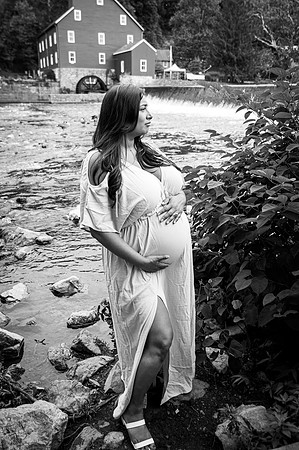 Maternity session by a river with a smiling male and female.