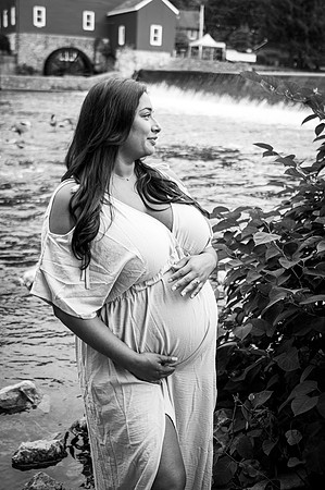 Maternity portrait near a waterfall featuring a standing couple.