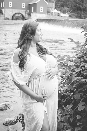 Maternity session near a river and waterfall with a smiling male and female.