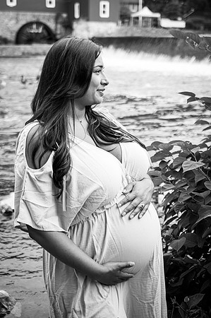 Maternity session by a river with a smiling male and female.