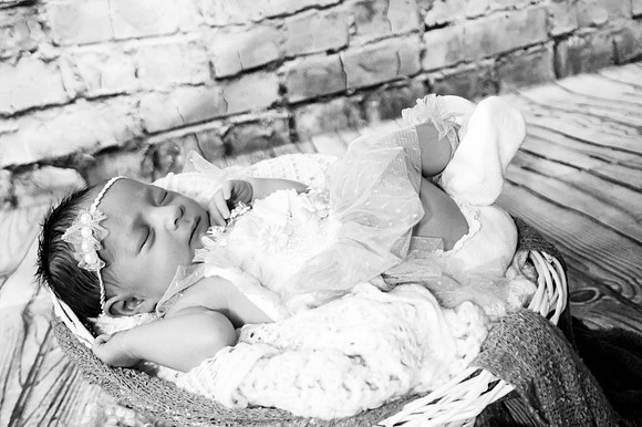 Black and white newborn portrait in a basket at Clinton studio with a smiling male child.