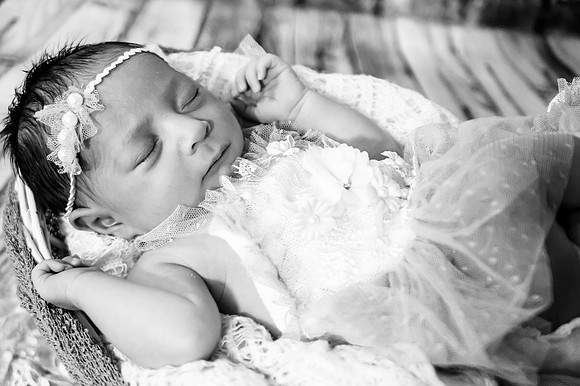 Black and white portrait of a smiling pregnant female with brown hair and eyes closed.