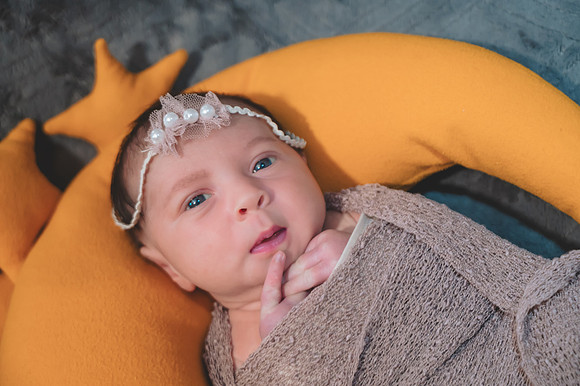 Black and white portrait of a newborn lying down with eyes open, captured at the Clinton studio.